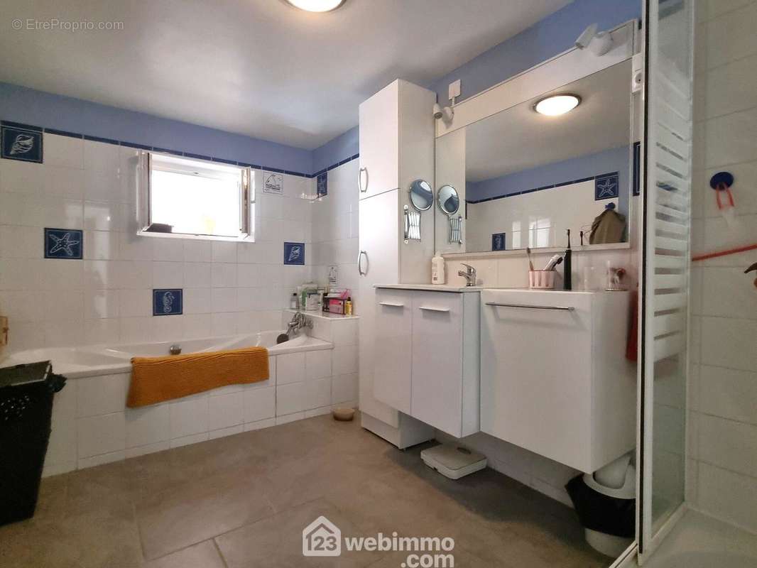 Une salle de bains (8 m2) avec baignoire et douche. - Maison à NEUVILLE-DE-POITOU