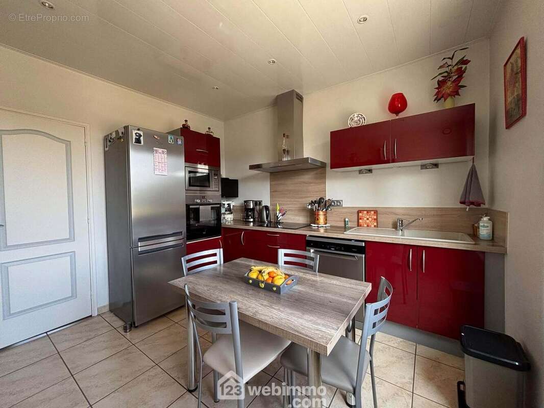 Attenante au séjour, la cuisine aménagée et équipée de 10 m2 dispose d&#039;un escalier pour accéder au niveau inférieur et au jardin. - Maison à DANGE-SAINT-ROMAIN