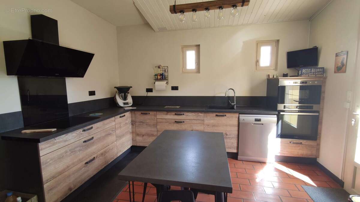 Une cuisine moderne et toute équipée avec accès à la terrasse - Maison à LES HERBIERS