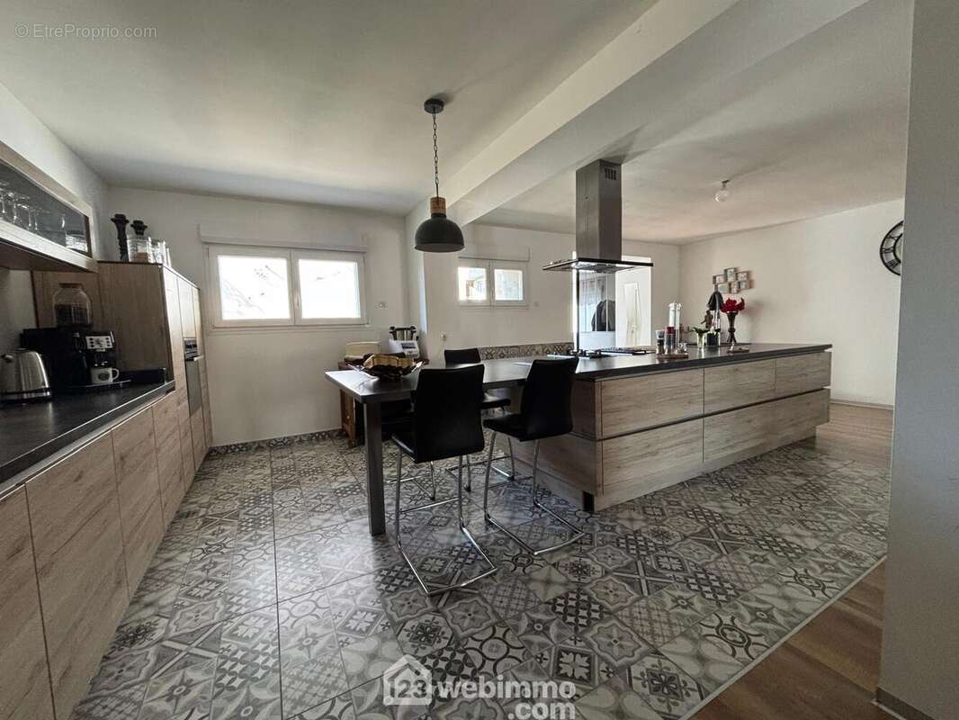 Cuisine aménagée fonctionnelle typé industriel avec de nombreux rangement, meubles sans poignées, ilot centrale avec grand casserole et espace repas, tout électroménager encastré... - Maison à VERDUN