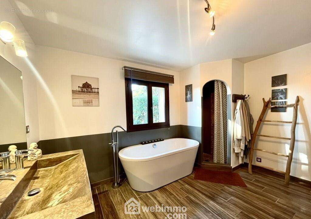 Une salle de bains spacieuse et lumineuse, alliant confort et élégance, avec baignoire îlot, douche, vasque en pierre naturelle et matériaux choisis. - Maison à SAINTE-MAXIME