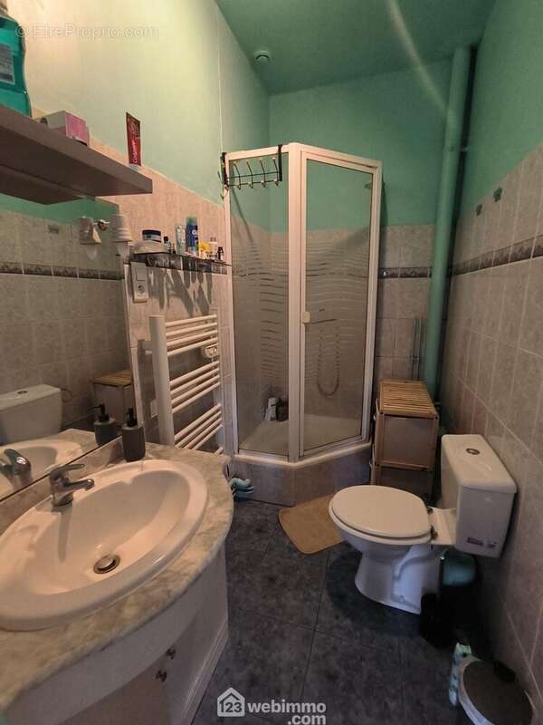 La salle d&#039;eau avec vasque sur meuble, douche, radiateur sèche serviettes et WC - Appartement à SOISSONS